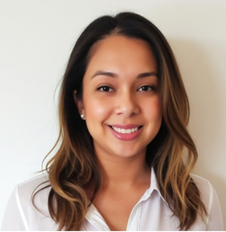 A woman with shoulder-length brown hair, wearing a white blouse, smiles at the camera against a plain light-colored background.