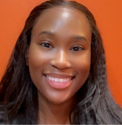 A woman with long black hair smiles at the camera in front of an orange background.