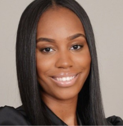 A woman with straight, long black hair and a black top smiles at the camera against a neutral background.