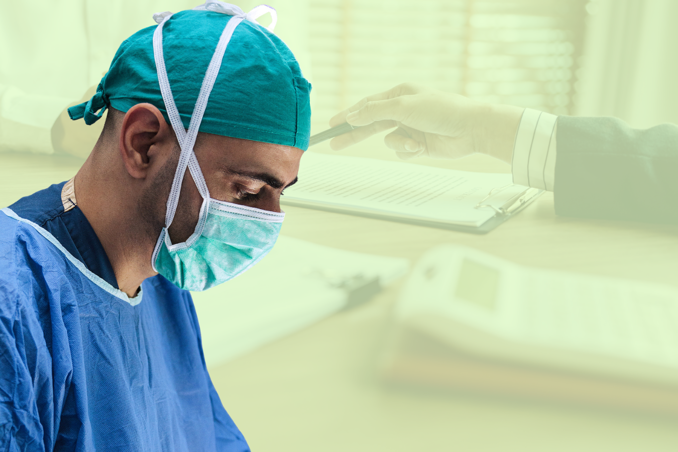 A surgeon in scrubs and a mask looks down, with a blurred background showing a person pointing at a document on a desk.